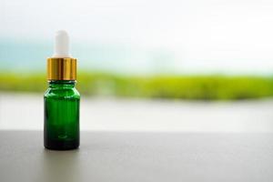 uma garrafa de vidro verde com conta-gotas em cima da mesa. conceito de óleo de aroma, cosméticos e pele de beleza.