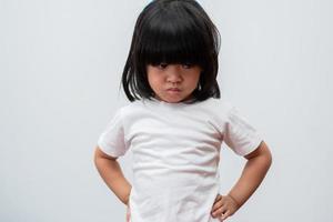 retrato de menina asiática com raiva e triste em fundo branco isolado, a emoção de uma criança quando birra e raiva, expressão mal-humorada emoção. conceito de controle emocional de criança foto