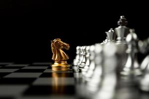 xadrez de cavalo dourado na frente de outro xadrez, conceito de líder deve ter coragem e desafio na competição, liderança e visão de negócios para uma vitória em jogos de negócios foto