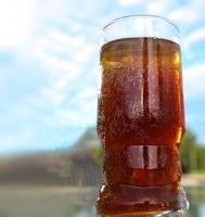 refrescantes coquetéis de verão laranja com cola e gelo contra um fundo de céu azul. vista de perto. foto