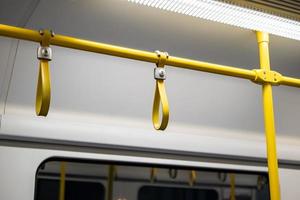 feche a mão de cabo de borracha - plástico segurando no trem de ligação ferroviária do aeroporto. foto