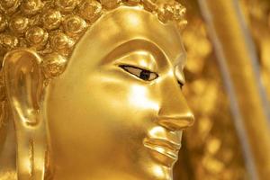 feche o rosto da estátua de Buda de ouro para segundo plano. foto