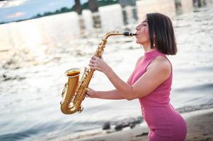 mulher tocando saxofone ao pôr do sol. foto