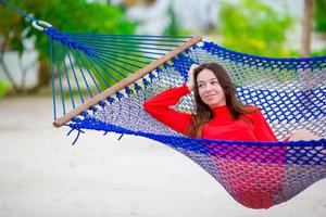 linda mulher relaxante na rede na praia tropical foto