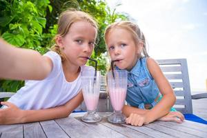 meninas tomando selfie e bebendo coquetéis saborosos no resort tropical foto