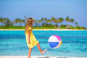 adorável menina brincando na praia com bola foto