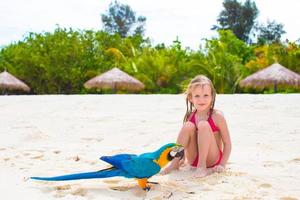 adorável menina na praia com papagaio colorido foto