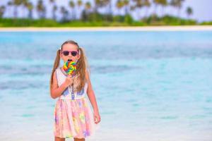 adorável menina com pirulito na praia tropical foto