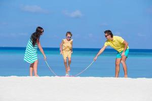 família feliz jogando juntos na praia branca foto