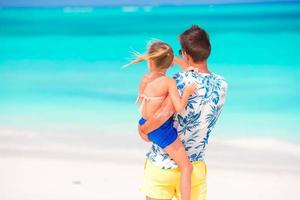 menina e jovem pai durante férias de praia tropical foto