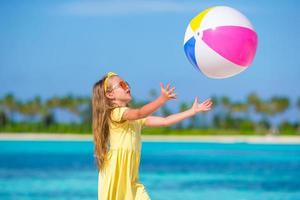 adorável menina brincando na praia com bola foto