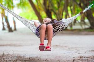 adorável garotinha em férias tropicais relaxando em uma rede foto