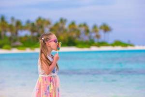 adorável menina com pirulito na praia tropical foto