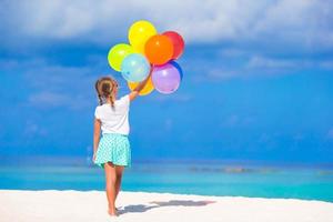 adorável menina brincando com balões na praia foto