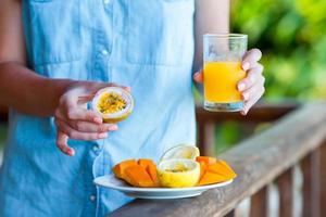 saborosas frutas exóticas - maracujá maduro, manga no café da manhã na mão feminina foto
