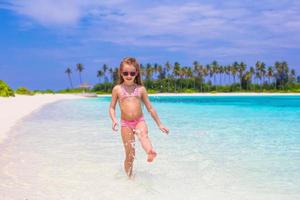 menina adorável na praia durante as férias de verão foto