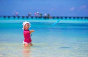 menina brincando com disco voador na praia wnite foto