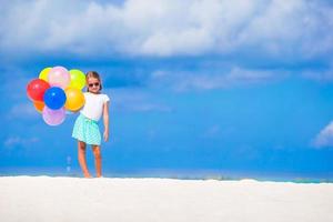 adorável menina brincando com balões na praia foto