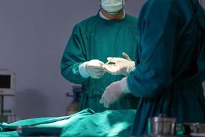 médicos profissionais realizando cirurgia. assistente entrega instrumentos para cirurgiões durante as operações. cirurgiões realizam operações.