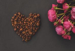 um coração de grãos de café na mesa e flores. foto