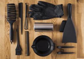 acessórios de cor preta para tingimento de cabelo em uma mesa de madeira. tigela, escova, pente, papel alumínio e outros acessórios de salão de cabeleireiro, vista superior. foto