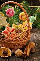 biscoitos de gengibre de natal e pirulitos em uma cesta em fundo de madeira velho foto