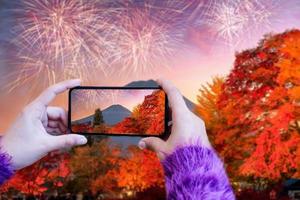 mão segurando o telefone inteligente tire uma foto da montanha fuji e fogos de artifício