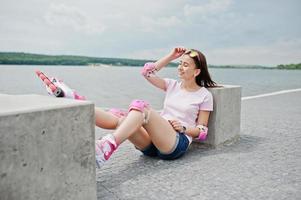 retrato de uma linda mulher sentada no chão ao lado do cubo de concreto usando patins e roupas casuais. foto