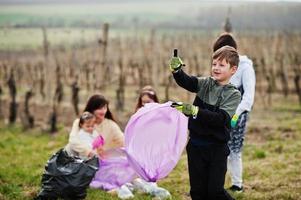 família com saco de lixo coletando lixo durante a limpeza nas vinhas. conservação ambiental e ecologia, reciclagem. foto