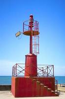 antigo farol de cor vermelha no horário de verão na vila italiana foto