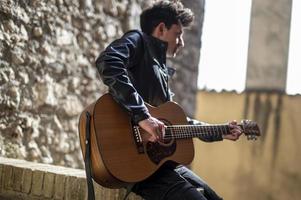 menino toca guitarra ao ar livre em um beco foto