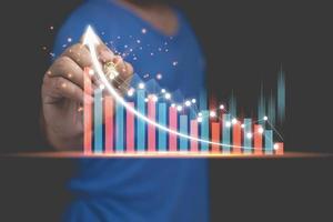 gráfico de gráficos de crescimento de negócios, finanças, negociação de ações, análise de investimentos e conceito de análise do mercado de ações. um homem usa um ponto de caneta no gráfico de crescimento de negócios mais alto, análise de mercado com espaço de cópia. foto