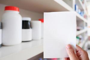 mão de farmacêutico com papel de prescrição em branco na farmácia foto