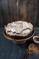 bolo de brownie redondo coberto com merengue e redemoinhos de chocolate no suporte de bolo rústico