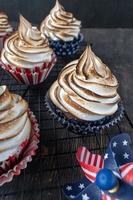 cupcakes vermelhos brancos e azuis com topos de redemoinho de merengue torrado foto