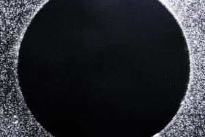 abstrato. círculo de farinha de trigo polvilhado, mancha redonda em preto. vista superior no quadro-negro. conceito de cozimento, cozinhar massa ou pastelaria. foto