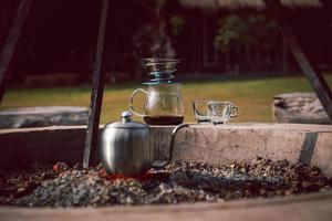 pingando café ao ar livre no parque natural com chaleira na fogueira. foto