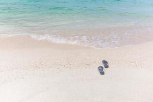 chinelos de conceito de férias tropicais em uma praia de areia. foto