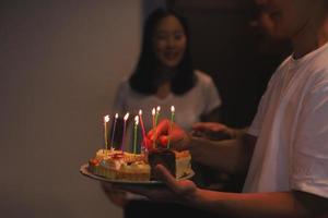 homem segurando o bolo de aniversário com velas para aniversariante em casa. foto