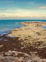 rochas na costa do mar com céu azul e nuvens foto