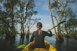 mulher velejando caiaque de mar na floresta de mangue foto