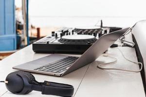 mesa de controle de som dj misturando com fone de ouvido e laptop na mesa ao ar livre. foto