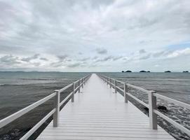 mulher adulta em pé na ponte branca no mar em dia mal-humorado foto