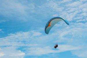 conjunto de parapente voando sobre o mar com água azul e praia em dia ensolarado. foto