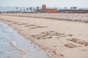 inscrições na areia com ondas do mar foto