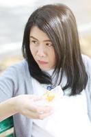 linda mulher asiática de vestido branco comendo lanches no parque. menina tailandesa e chinesa. foto