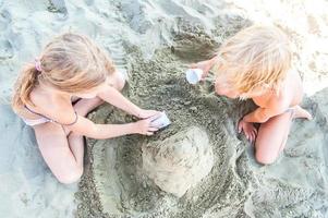 crianças brincando na praia com areia foto