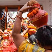 mulheres com kalash na cabeça durante o templo jagannath mangal kalash yatra, devotos hindus indianos carregam potes de barro contendo água sagrada com um coco no topo foto