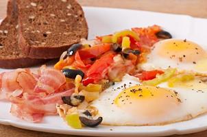 café da manhã - ovos fritos com bacon, tomate, azeitonas e fatias de queijo foto