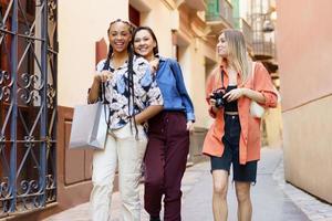 alegres fêmeas multirraciais passeando juntos depois das compras foto